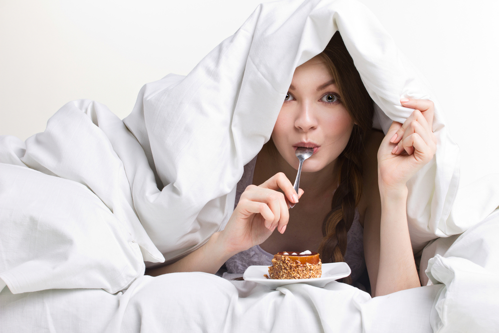Woman eats food in bed