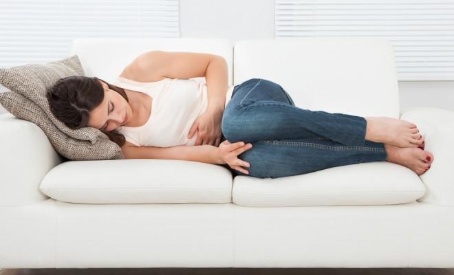 Woman laying on couch suffering from symptoms of PMS