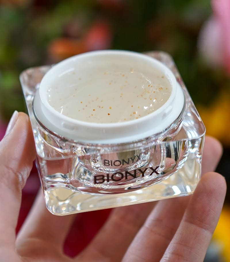Holding an open jar of Bionyx skincare exfoliator